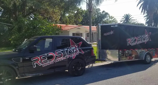 Black Range Rover with the Red Star wrap towing the black Red Star equipment trailer on a residential street