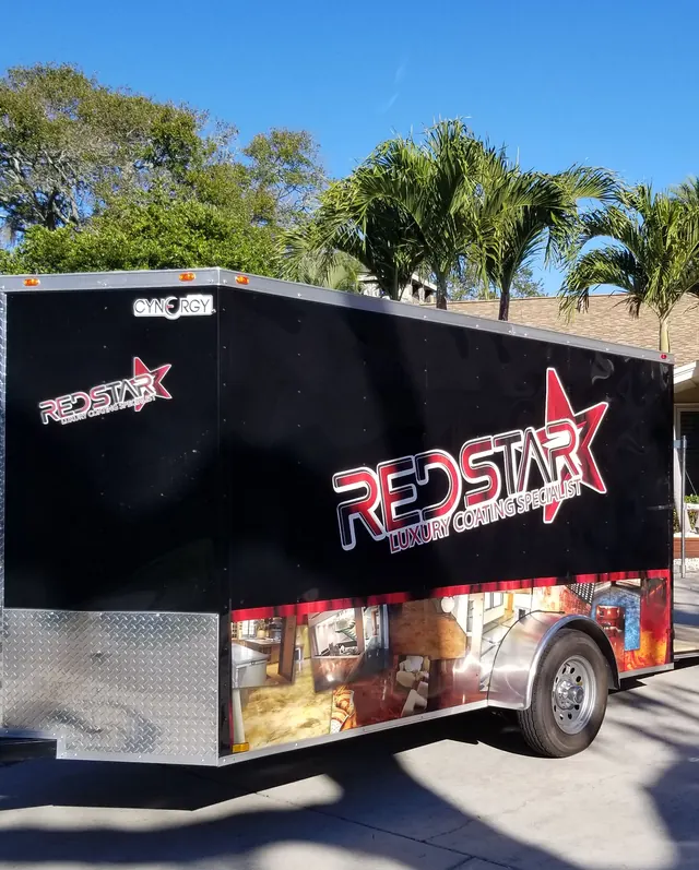 Black enclosed equipment trailer with the Red Star logo parked under palm trees