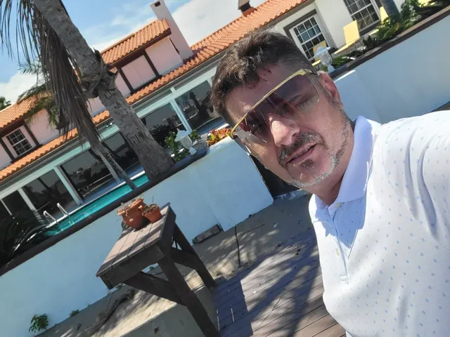 Red Star's owner taking a selfie on the pool deck of a white stucco home with a red tile roof