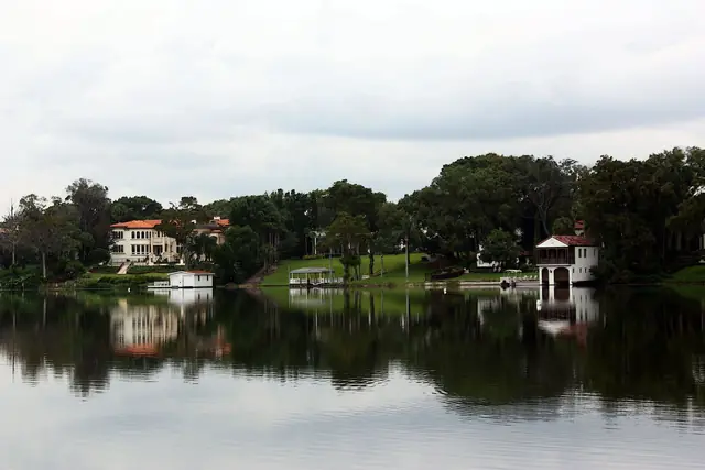 Calm water and oak-lined shoreline on Lake Maitland, Winter Park, with lakefront homes in the distance