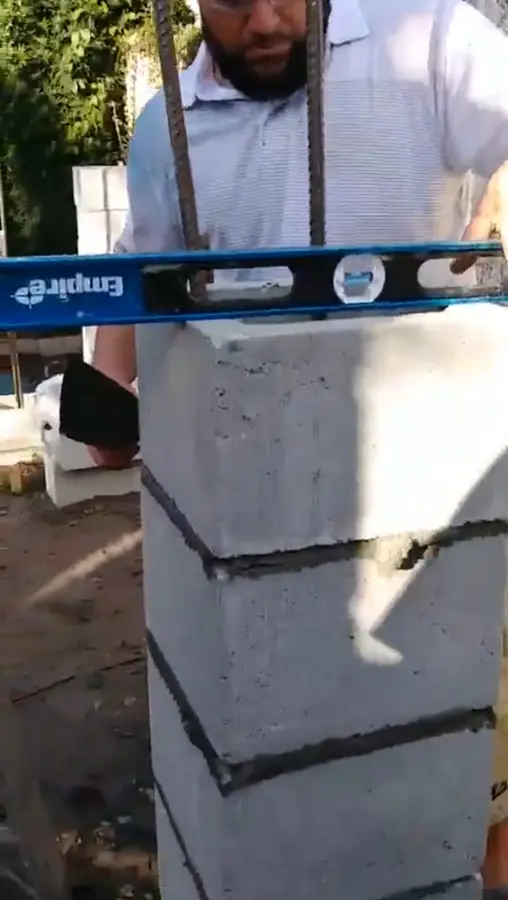 Red Star crew member holding a level across the top of a concrete block column with rebar, Winter Park, 2017