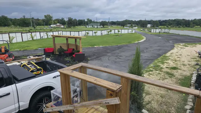 View from the finished deck railing over a gravel drive and lawn, with a white pickup truck parked below